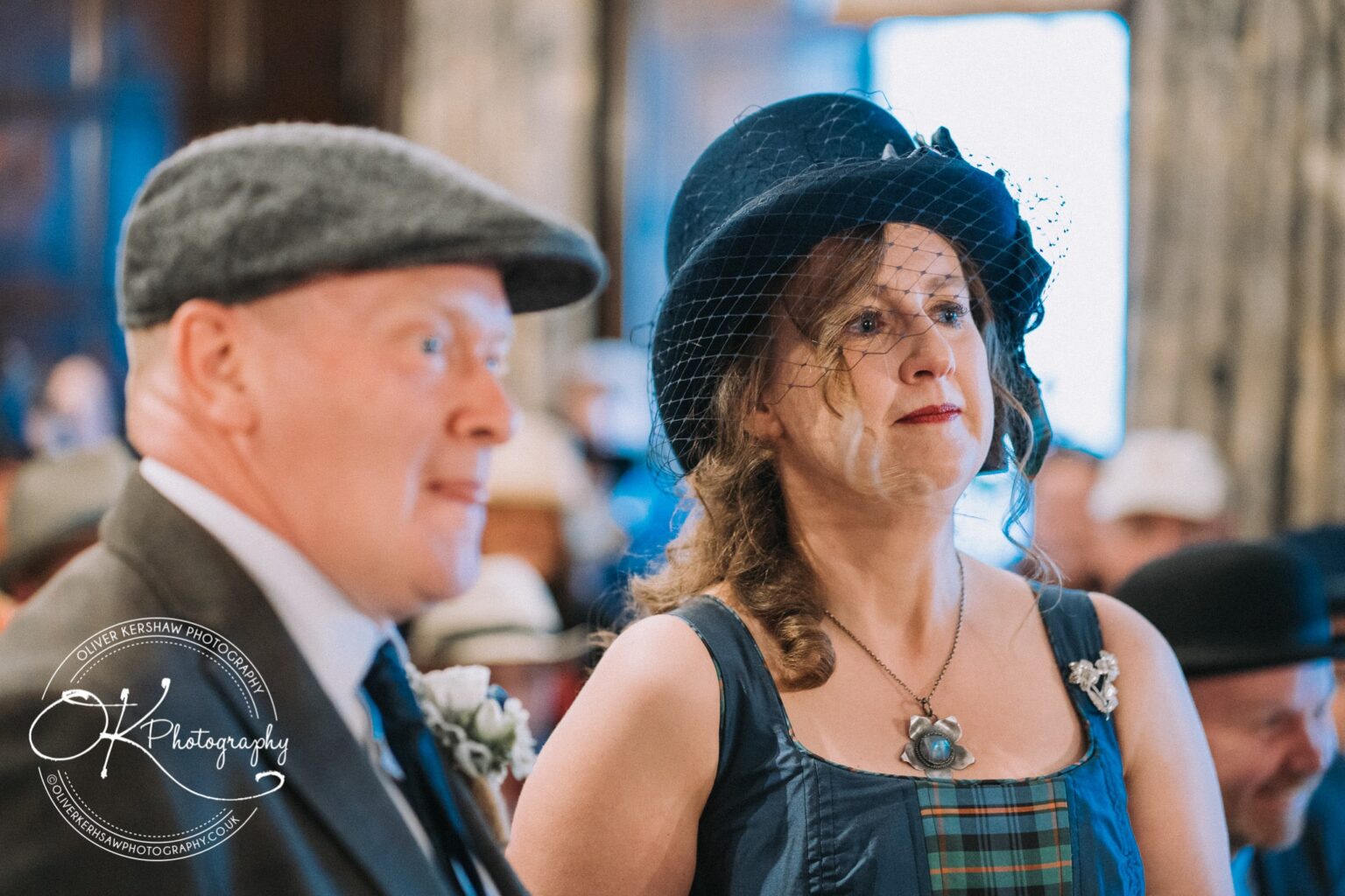 Wedding Photography George Hotel Stamford A man and woman in vintage attire at the George Hotel Stamford; the woman wears a dark hat with a net veil, and the man wears a flat cap.