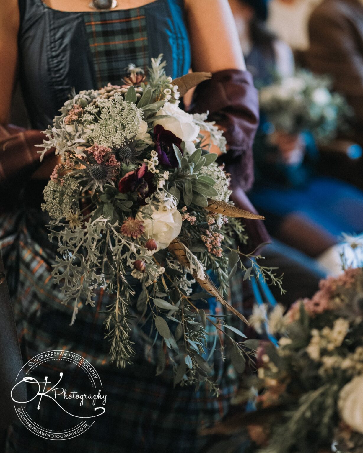 Wedding Photography George Hotel Stamford Person holding a detailed bouquet of mixed flowers and greenery, wearing a dress with tartan accents, and a shawl covering their arms.
