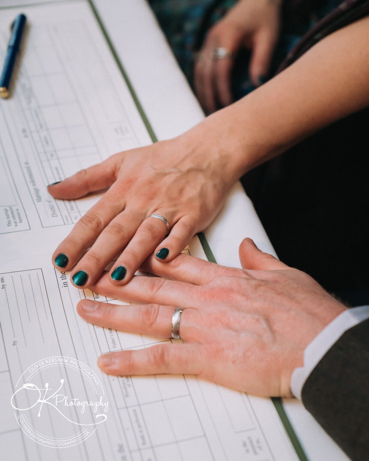 Wedding Photography George Hotel Stamford Hands of two people wearing wedding rings, placed over a marriage certificate.