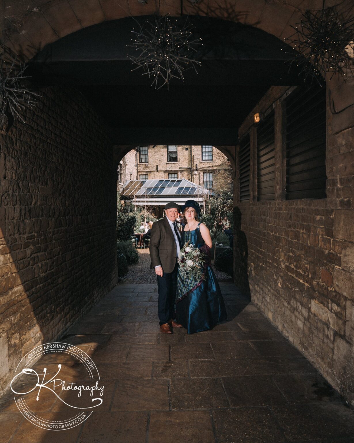 Wedding Photography George Hotel Stamford A couple posing under a stone archway at the George Hotel in Stamford, with a courtyard visible in the background.