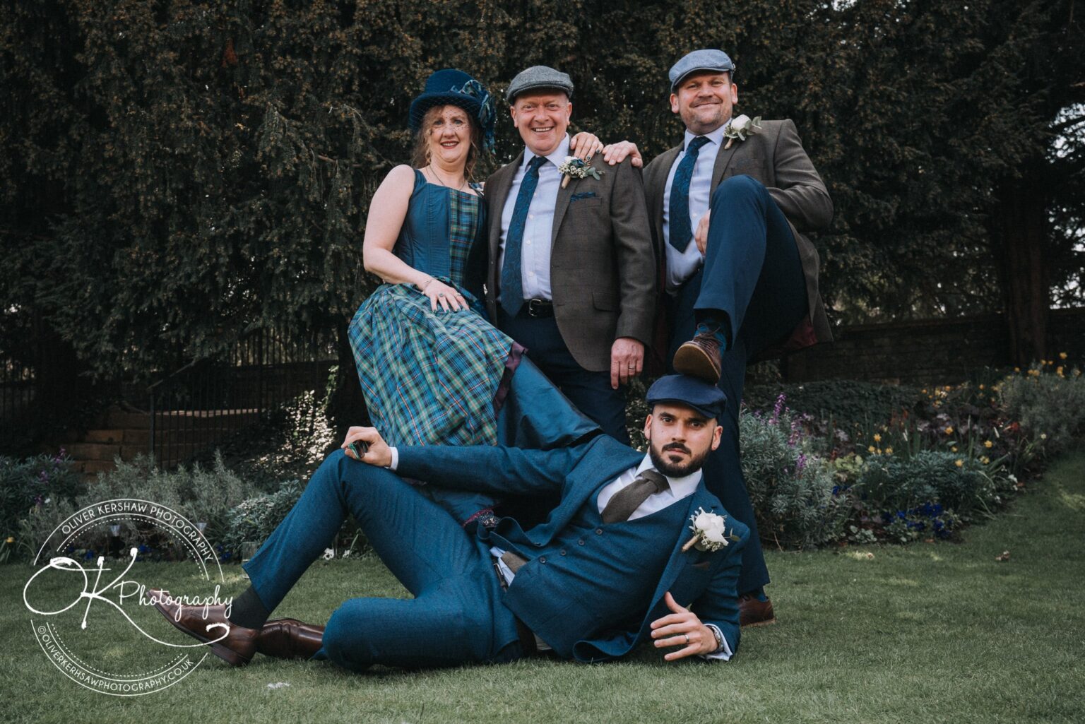 Wedding Photography George Hotel Stamford Four people in formal attire and flat caps posing playfully in a garden at George Hotel Stamford.