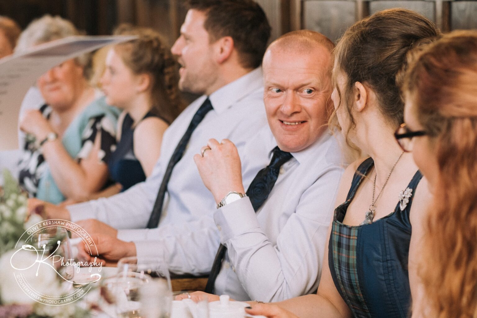 Wedding Photography George Hotel Stamford People sitting at a wedding reception, smiling and talking to each other at a dining table.