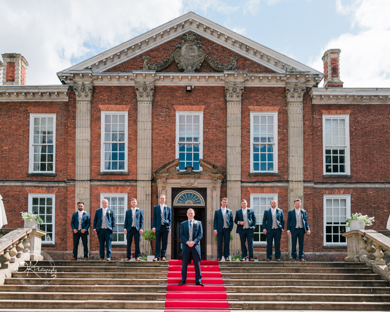 A group of men in suits standing on the steps of Bosworth Hall Hotel with a red carpet.