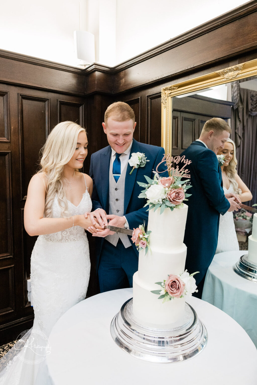 A bride and groom cutting a wedding cake decorated with flowers at Bosworth Hall Hotel.