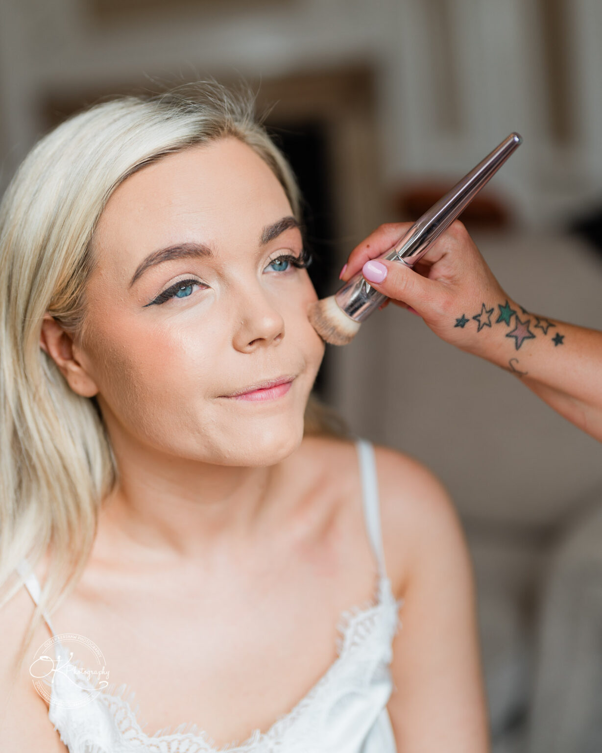 Woman having makeup applied on her face with a brush.