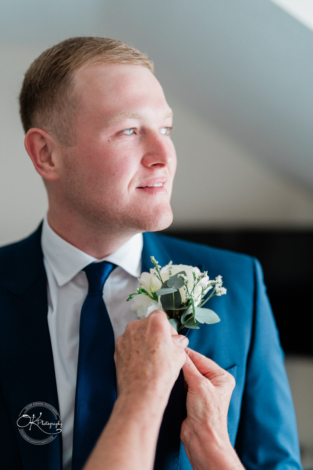 A person in formal attire having a boutonniere pinned to their suit.