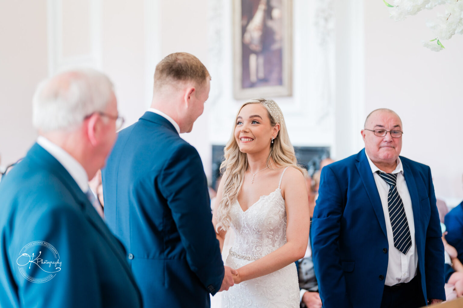 Bride and groom holding hands, smiling, with two men in suits standing nearby during a wedding ceremony at Bosworth Hall Hotel.