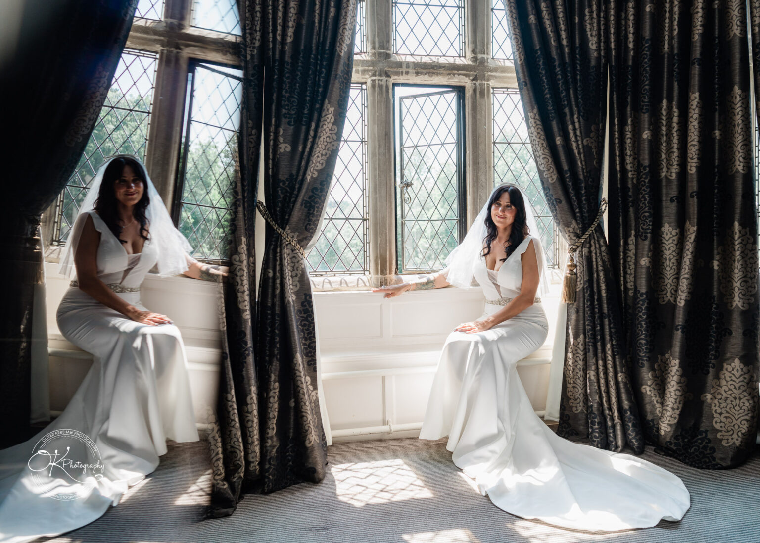Rothley Court Hotel wedding photography A bride in a white gown and veil sits on a windowsill with her reflection visible beside her, surrounded by large windows and dark curtains.