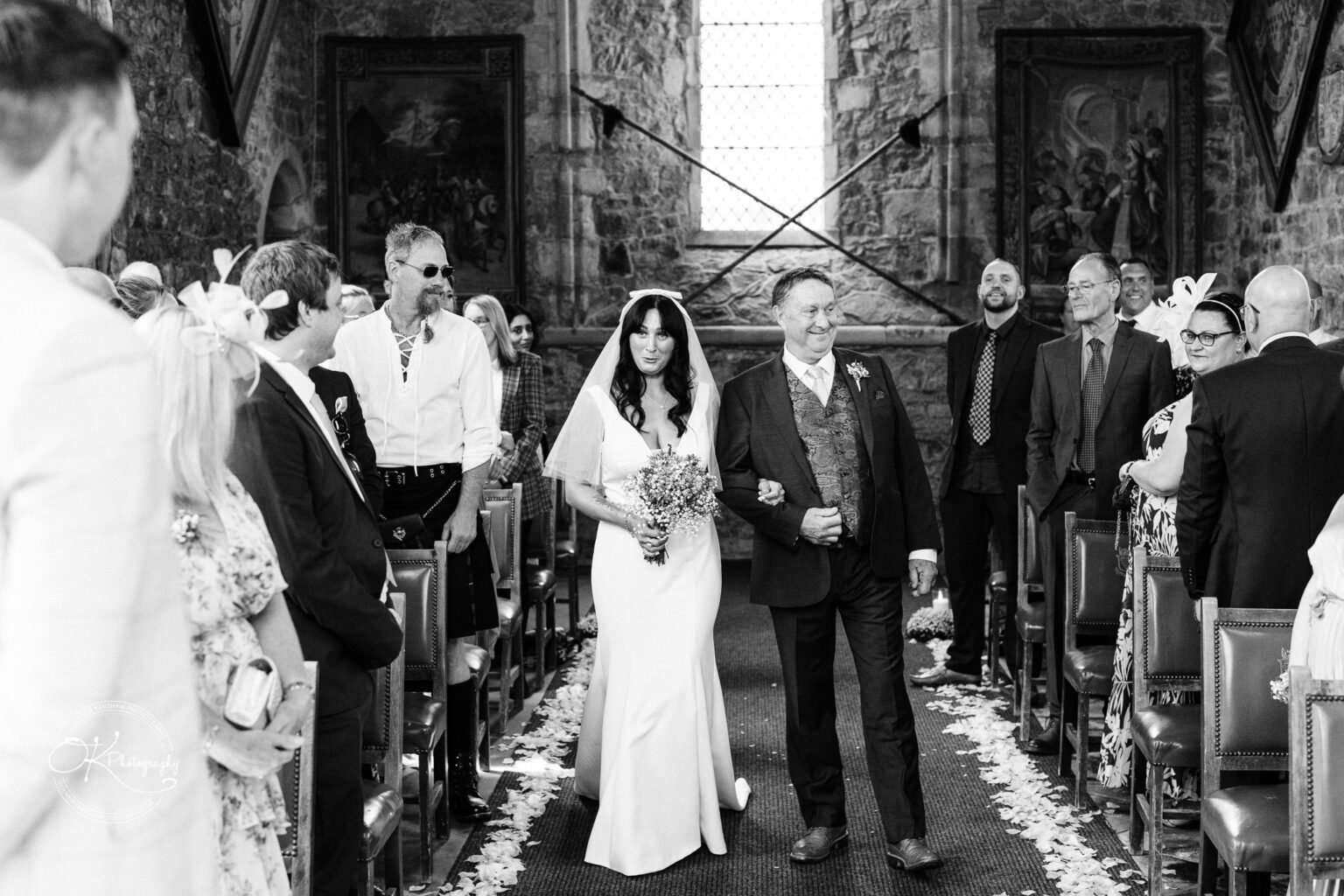 Rothley Court Hotel wedding photography Bride walking down the aisle with an older man, surrounded by wedding guests in a church.