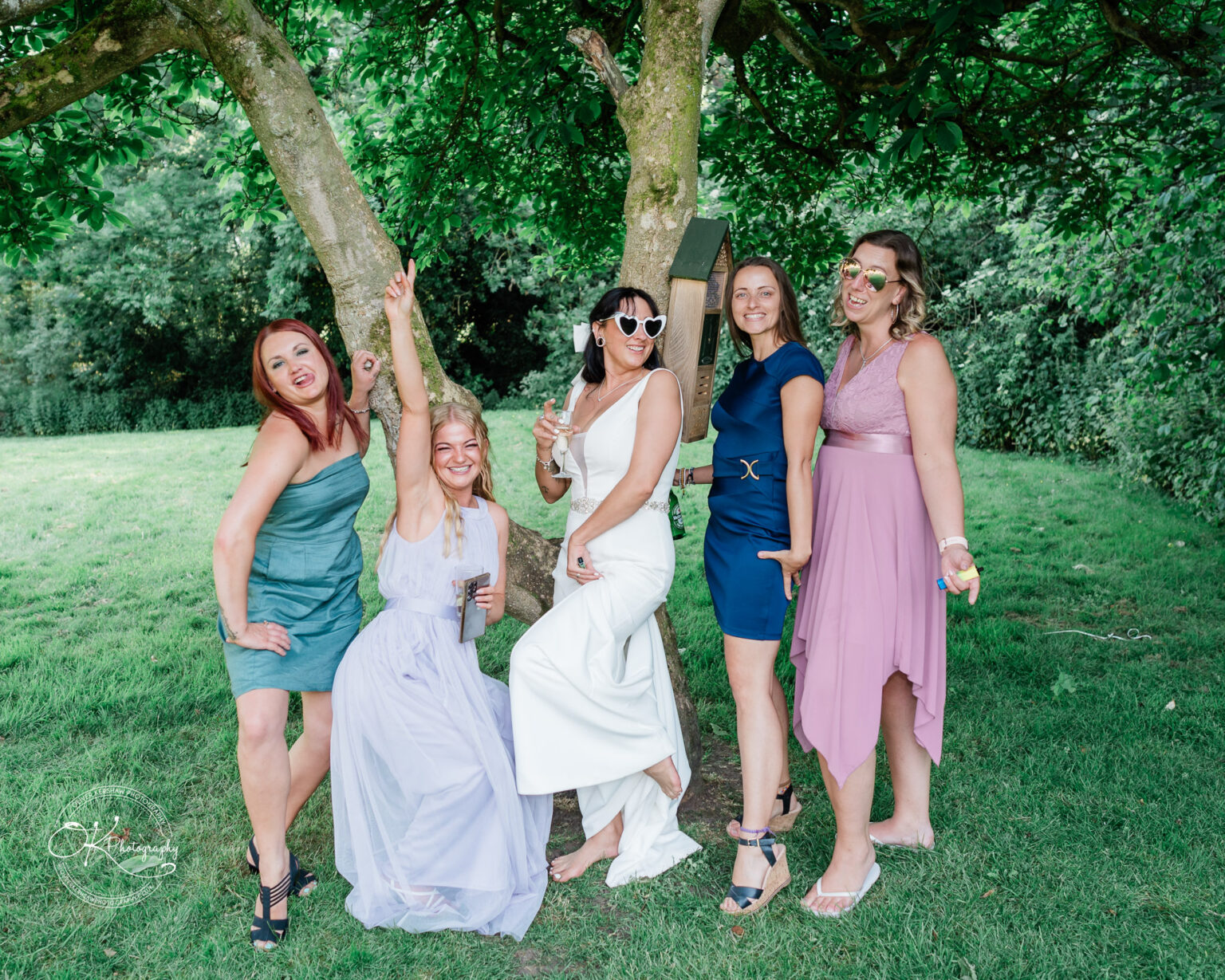 Rothley Court Hotel wedding photography Five women in dresses posing together under a tree, smiling and laughing.