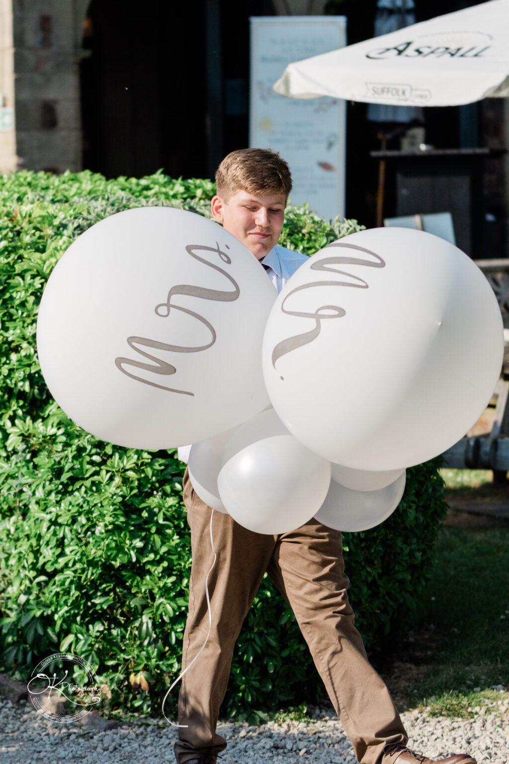 Rothley Court Hotel wedding photography A person holding large white balloons with the words "Mrs." and "Mr." written on them.