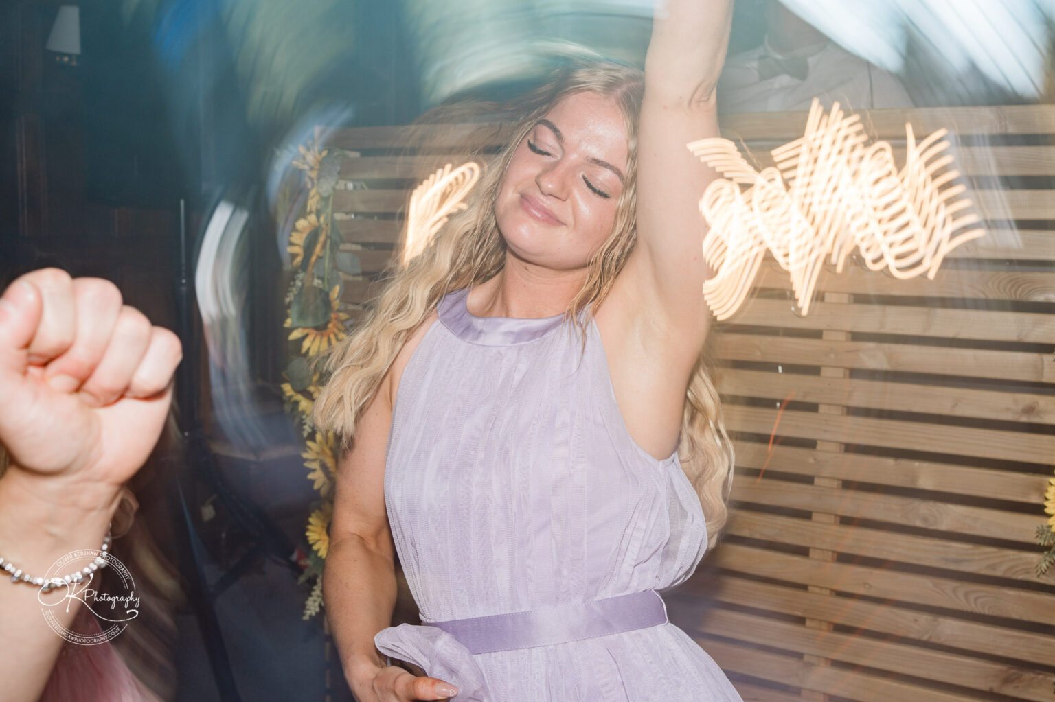 Rothley Court Hotel wedding photography Woman in a lilac dress dancing joyfully with eyes closed and arm raised.