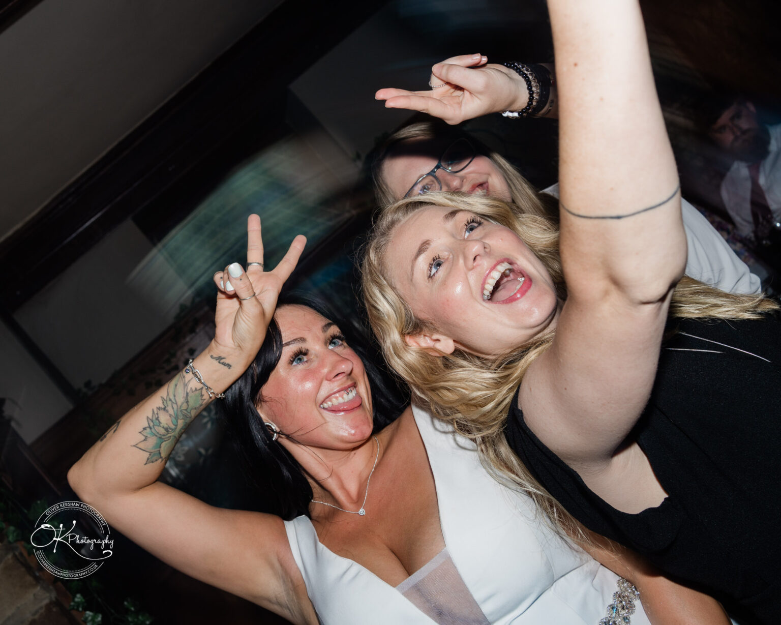 Rothley Court Hotel wedding photography Three women at a party smiling and posing for a selfie, two of them making peace signs.