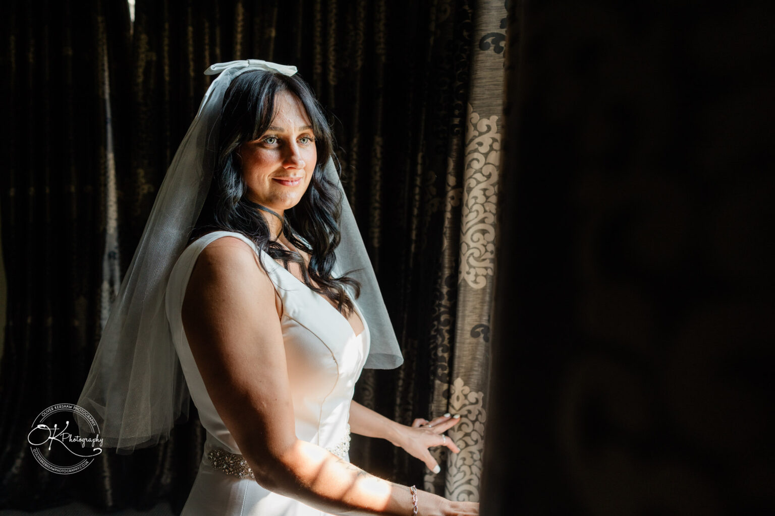 Rothley Court Hotel wedding photography Bride in a white dress and veil standing by patterned curtains.