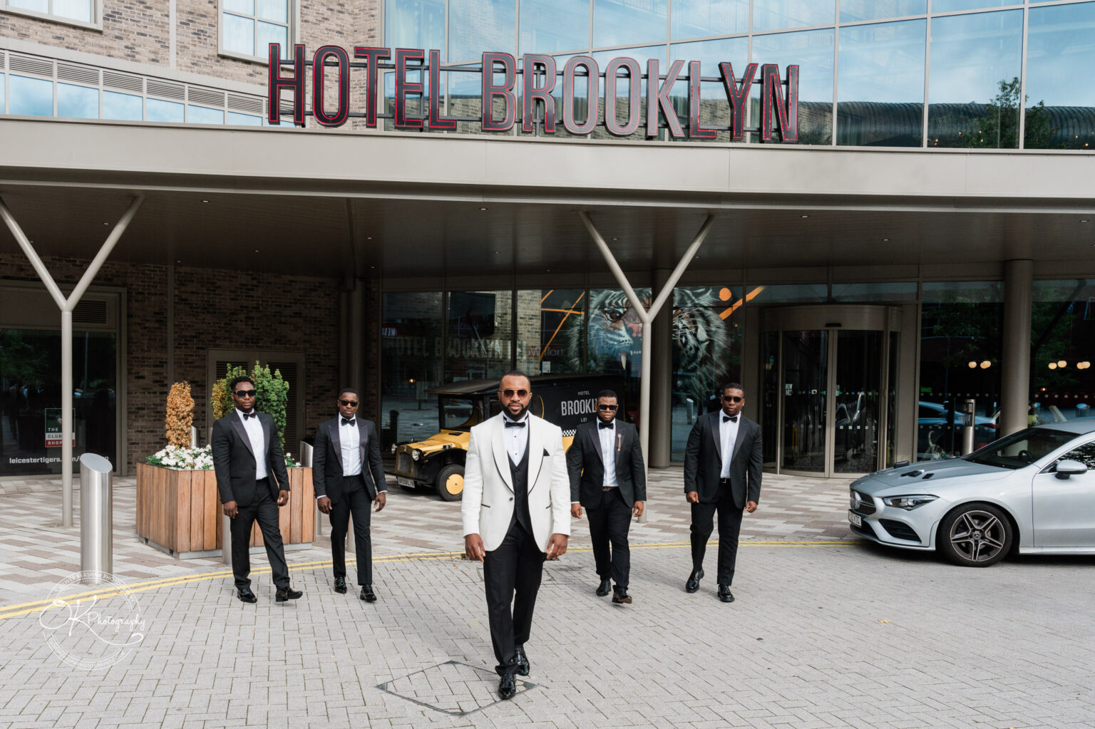 Symphony Rooms Wedding Photography Five men in formal attire standing in front of Hotel Brooklyn.