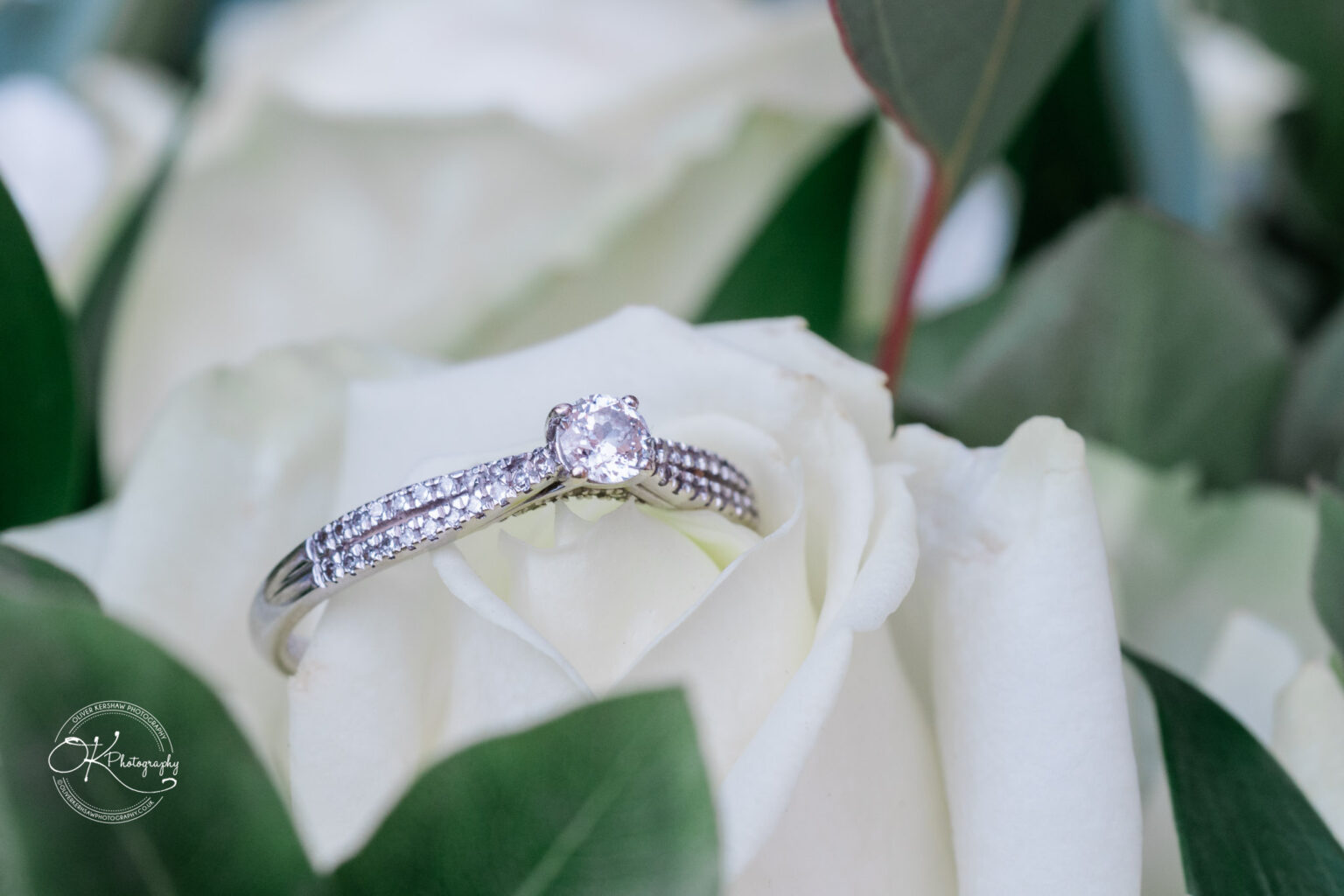 Symphony Rooms Wedding Photography A diamond engagement ring placed on a white rose.