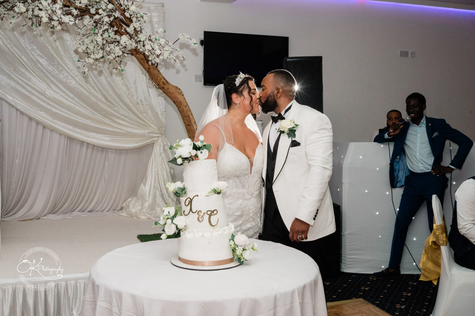 Symphony Rooms Wedding Photography Bride and groom kissing in front of a wedding cake.