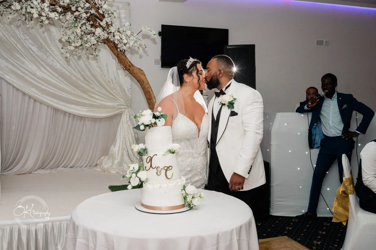 Bride and groom kissing in front of a wedding cake.