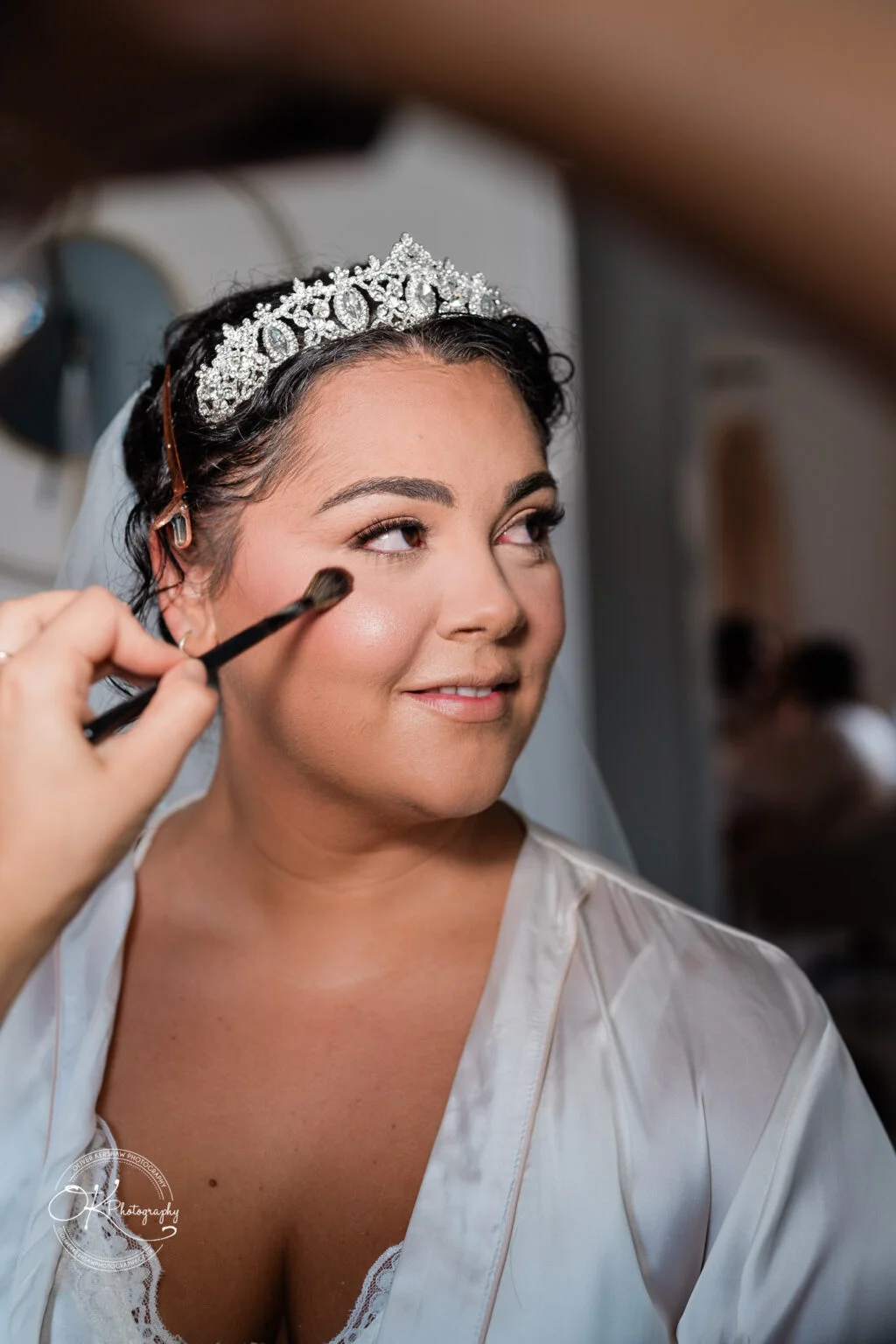 A bride with a tiara having her makeup applied.