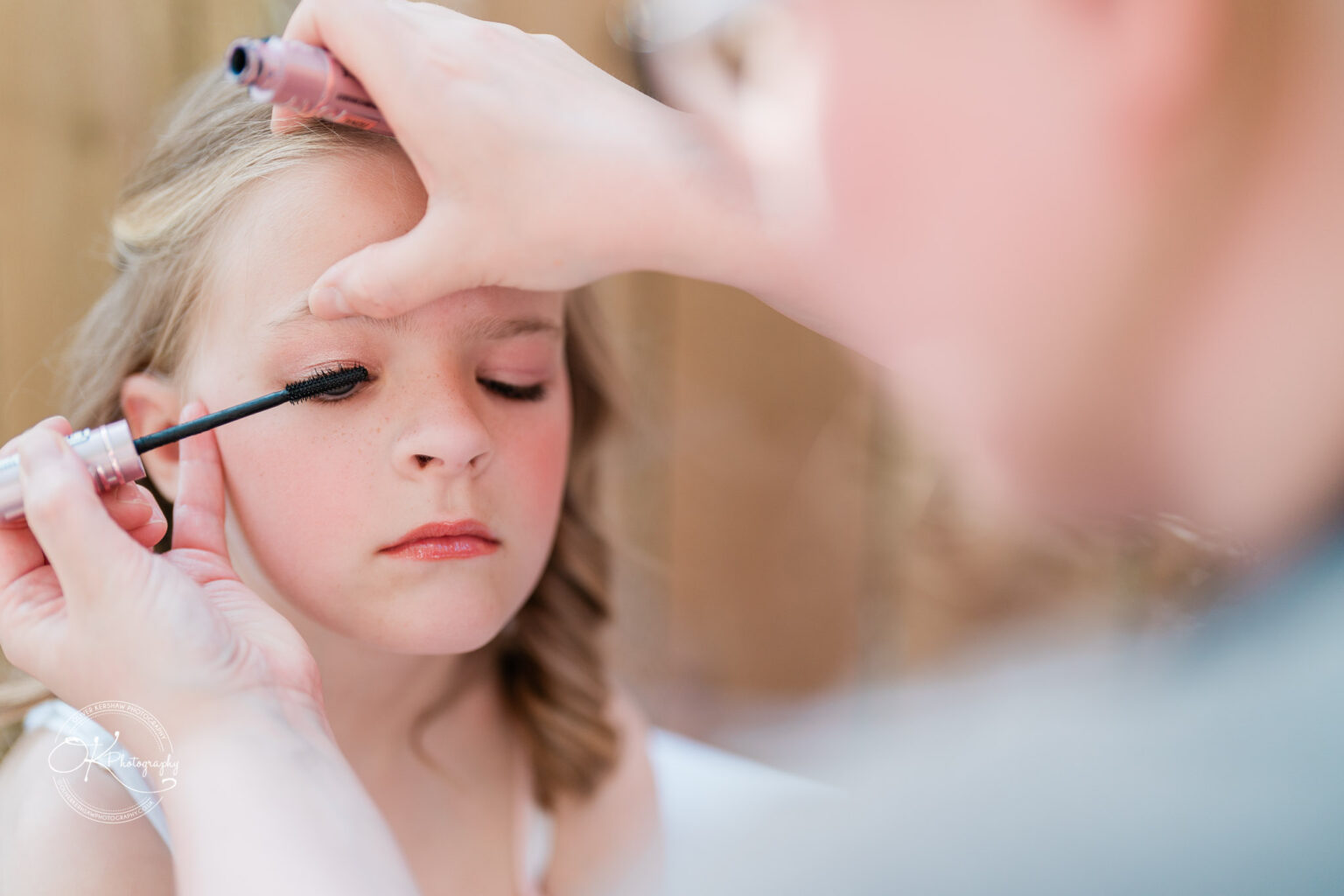 The Old Stables Wedding Photography A young girl is having mascara applied to her eyelashes by an adult.