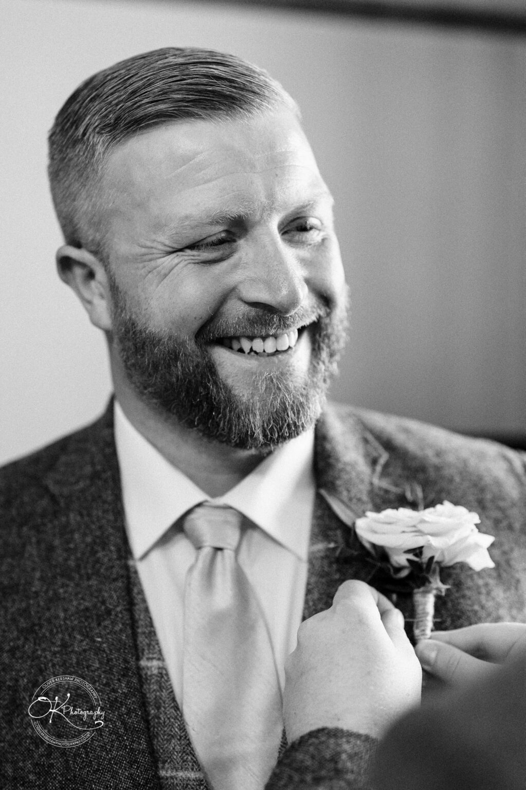 The Old Stables Wedding Photography A smiling man in a suit has a boutonnière pinned to his jacket.