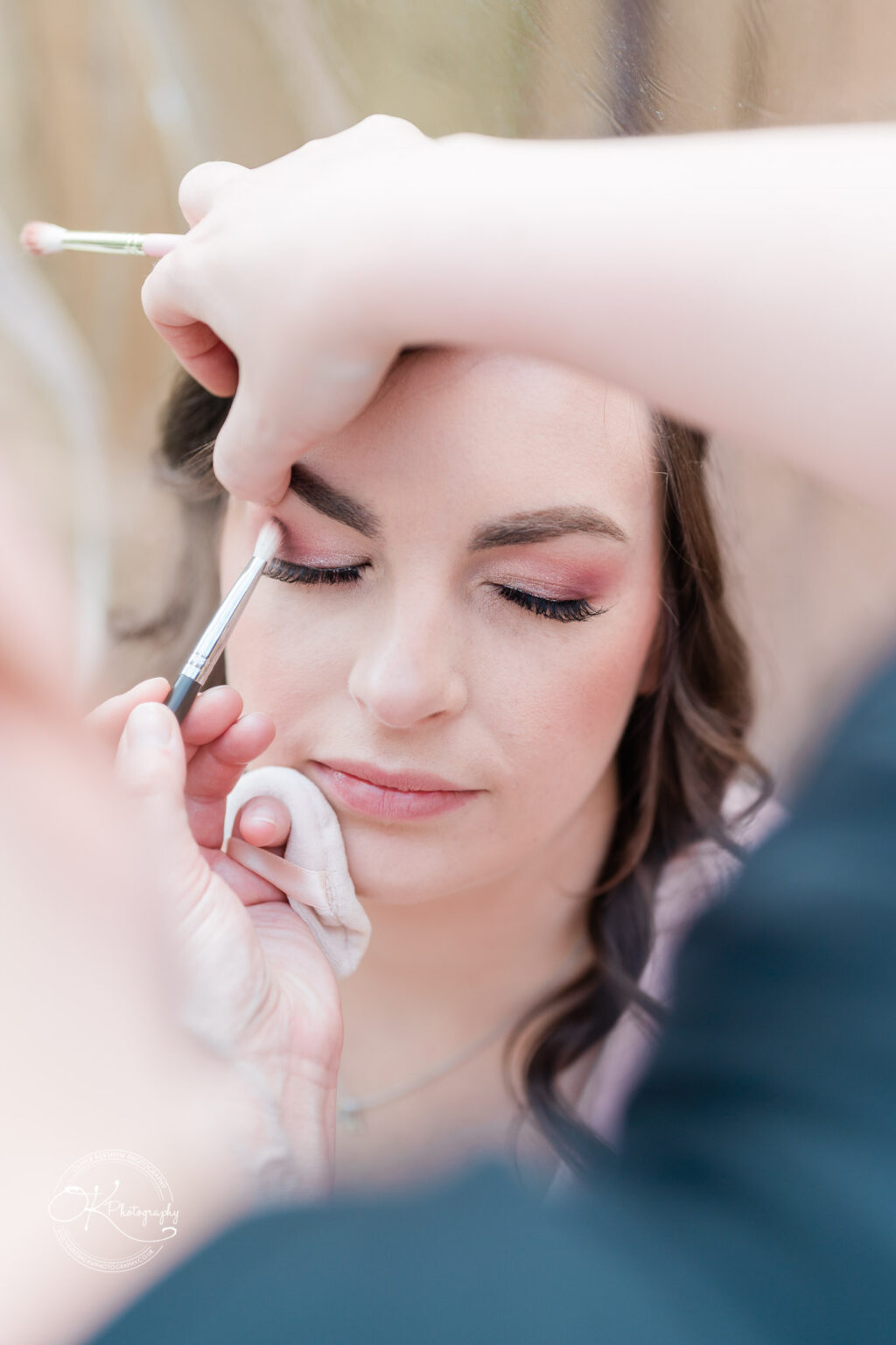 The Old Stables Wedding Photography A makeup artist applying makeup to a woman's eyes.