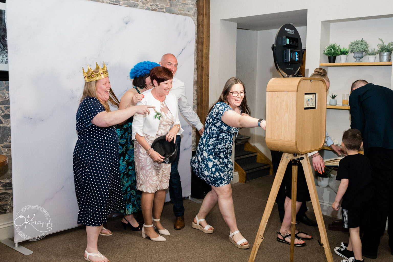 The Old Stables Wedding Photography Guests at a wedding having fun in a photo booth at The Old Stables, some wearing props like a crown and a blue hat.