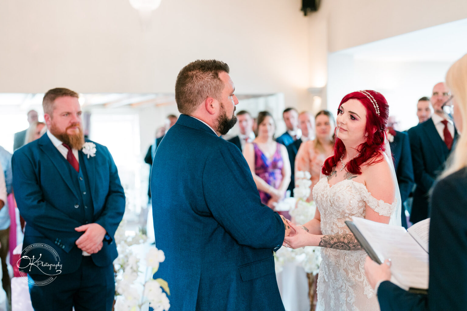 The cottage hotel - Wedding Photography A couple exchanging vows during a wedding ceremony, with guests standing in the background.