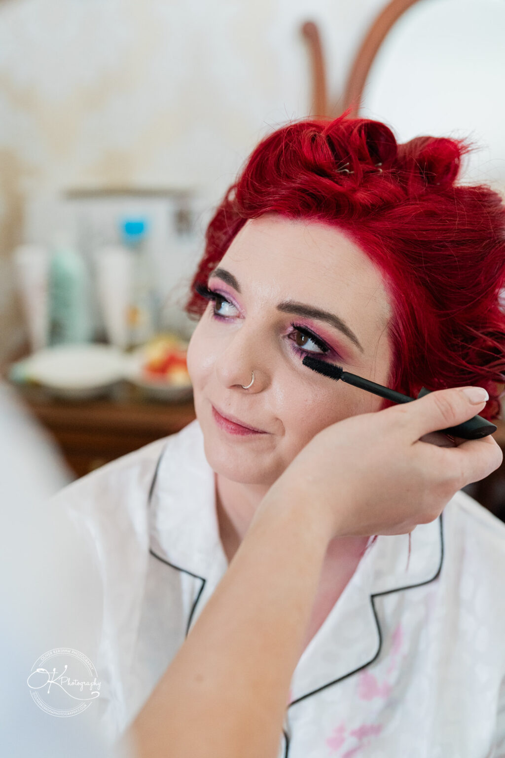 The cottage hotel - Wedding Photography A person with red hair is having mascara applied to their eyelashes.