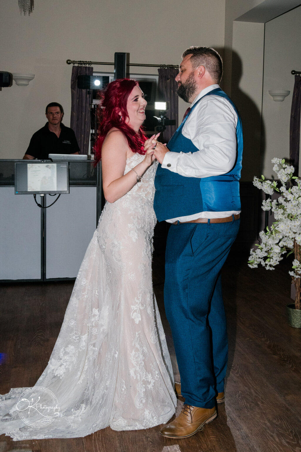 The cottage hotel - Wedding Photography A bride and groom dancing at their wedding reception, with the groom in a blue suit and the bride in a lace gown.