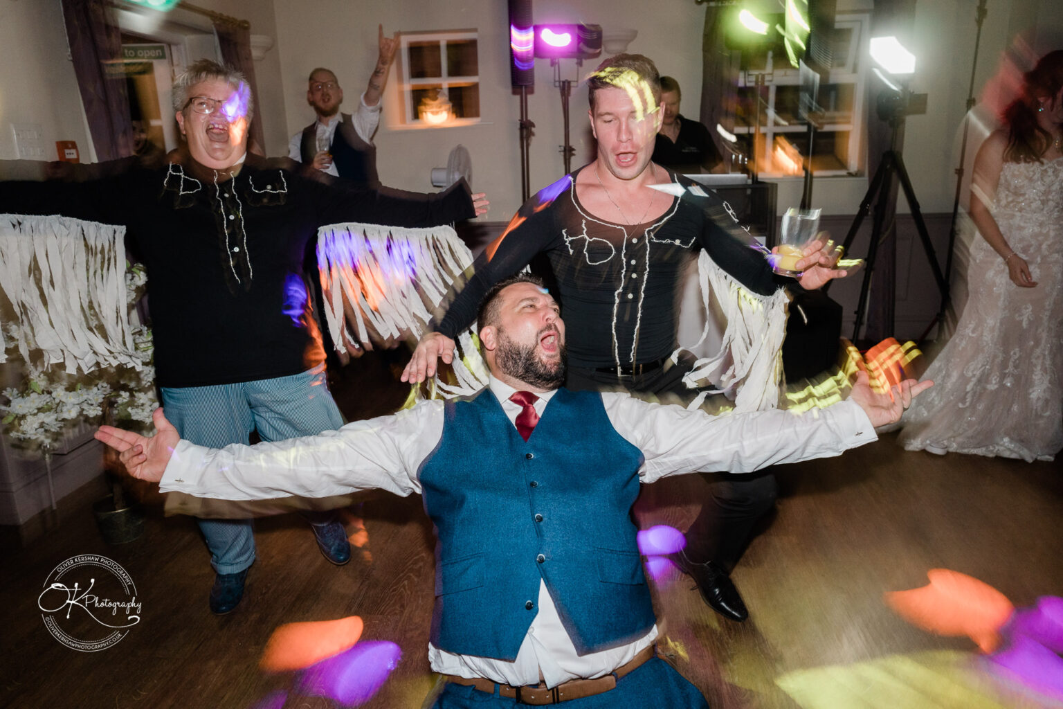 The cottage hotel - Wedding Photography People dancing energetically at a wedding reception with colourful lights.