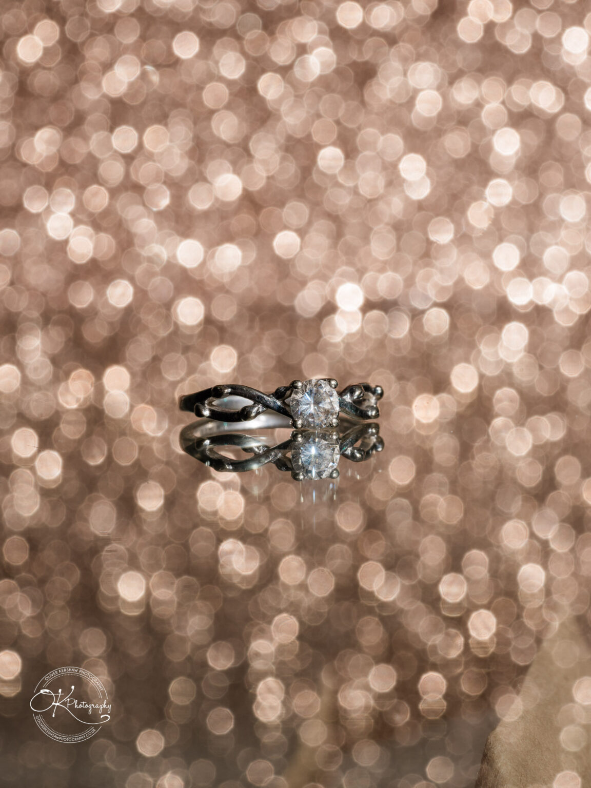 Close-up of a diamond engagement ring and wedding band with a glittering, bokeh background.
