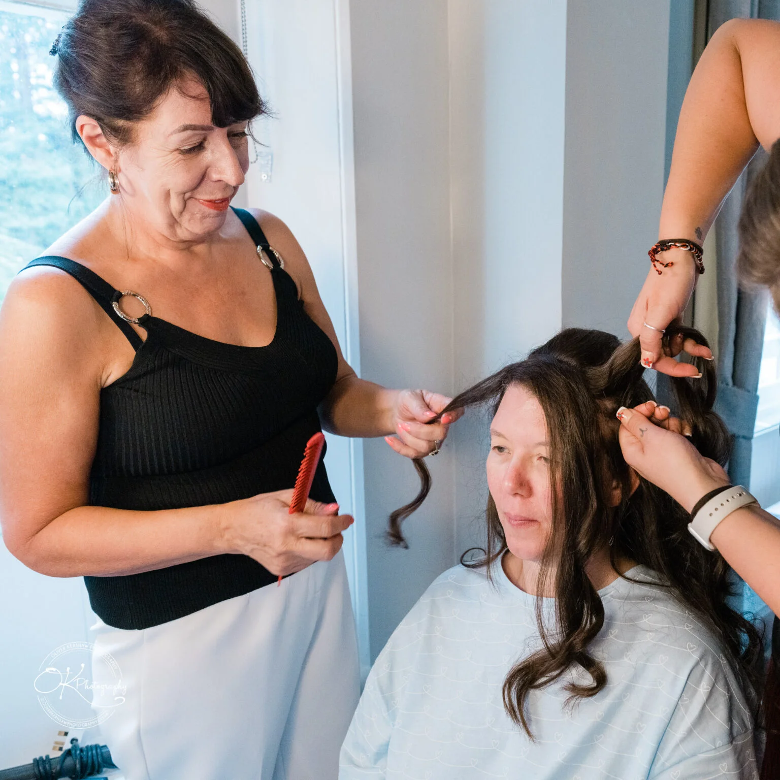 Makeney Hall Hotel - Wedding Photography A woman having her hair styled by two hairdressers at Makeney Hall Hotel.