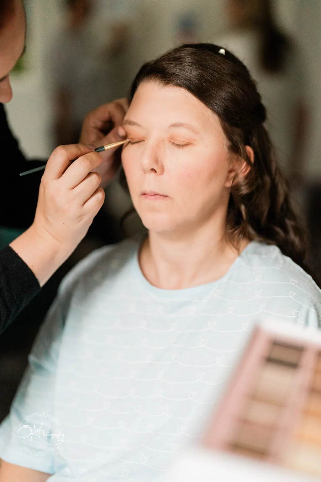 Makeney Hall Hotel - Wedding Photography A woman getting her makeup done with eyes closed.
