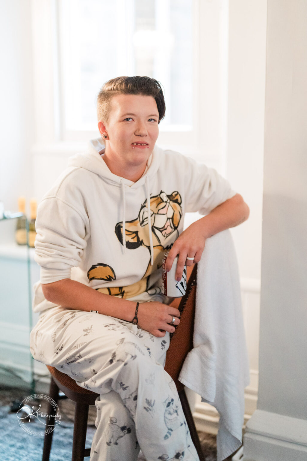 Person in pyjamas sitting on a chair, holding a can of Pepsi Max.