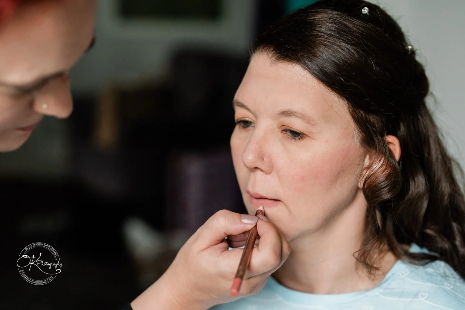 Makeney Hall Hotel - Wedding Photography Woman having lip makeup applied with a lip pencil by a makeup artist.