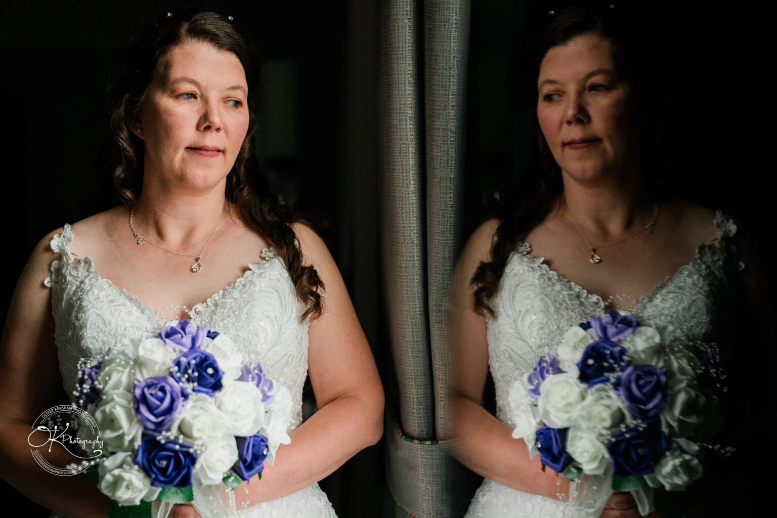 Makeney Hall Hotel - Wedding Photography A bride in a white dress holding a bouquet of white and purple flowers stands by a reflective surface, showing her reflection.