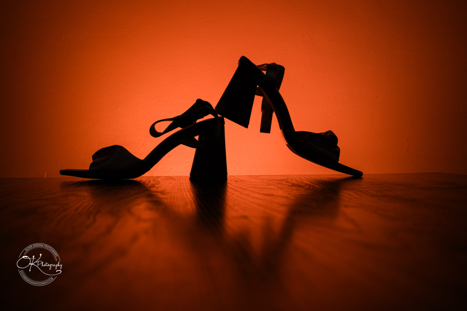 Silhouette of high-heeled shoes against an orange background.