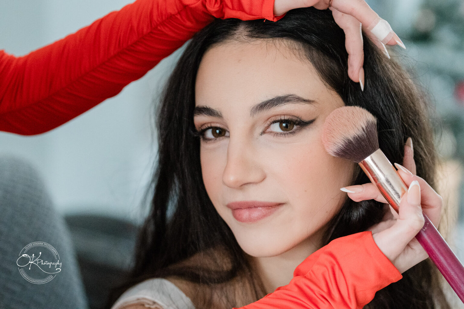 A woman having makeup applied to her face with a brush.