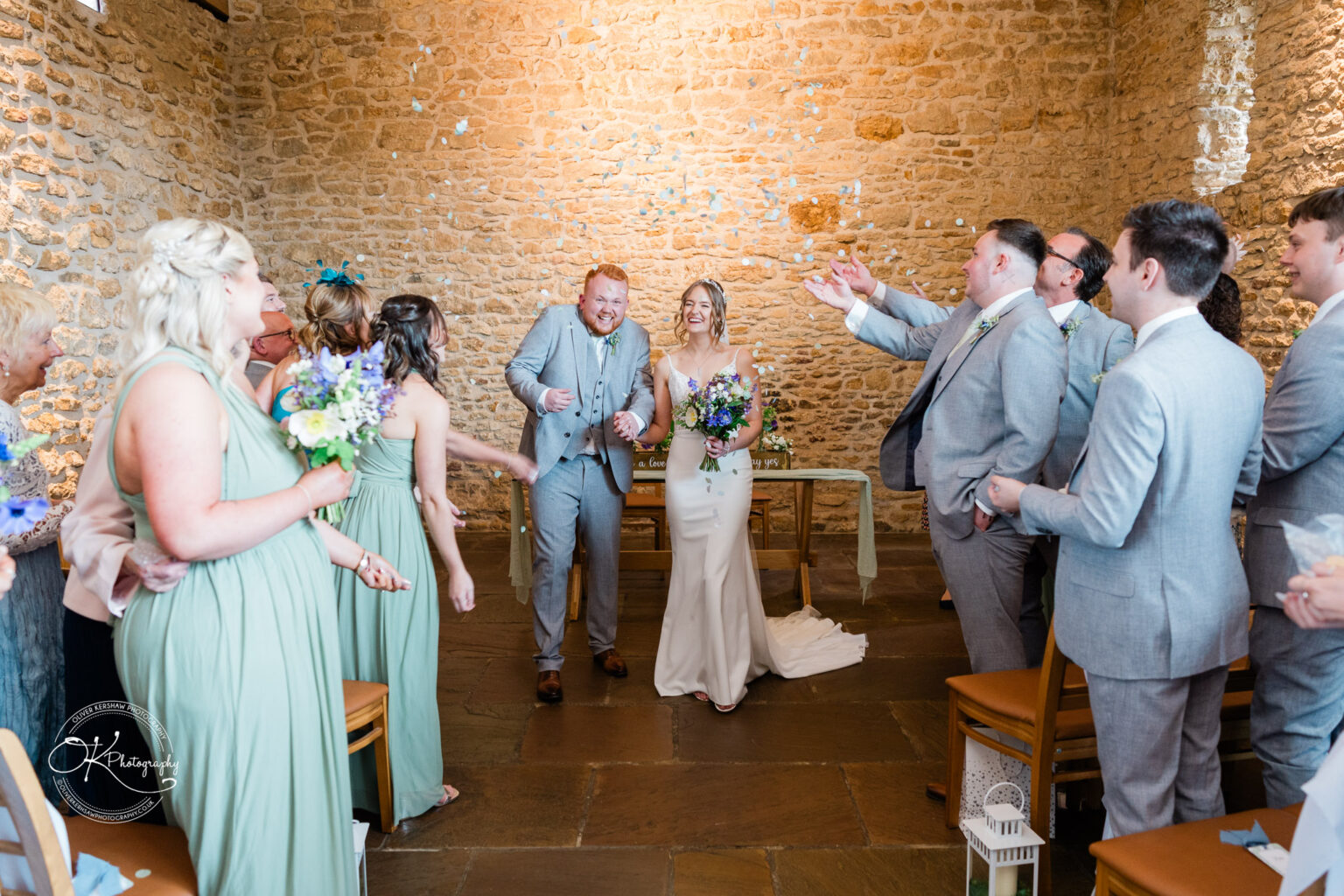 Bride and groom exiting ceremony at Dodford Manor with confetti