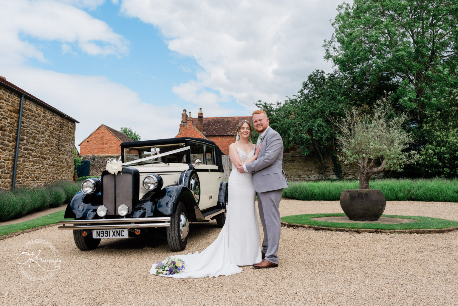 Bride and groom posing with a classic vintage car at Dodford Manor