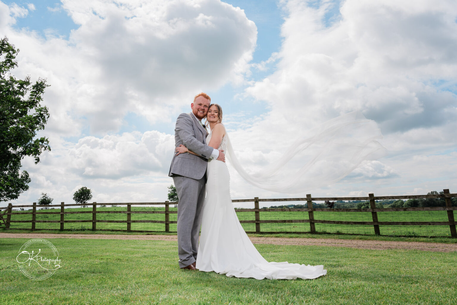 Bride and groom embracing on the green lawn with a scenic view at Dodford Manor
