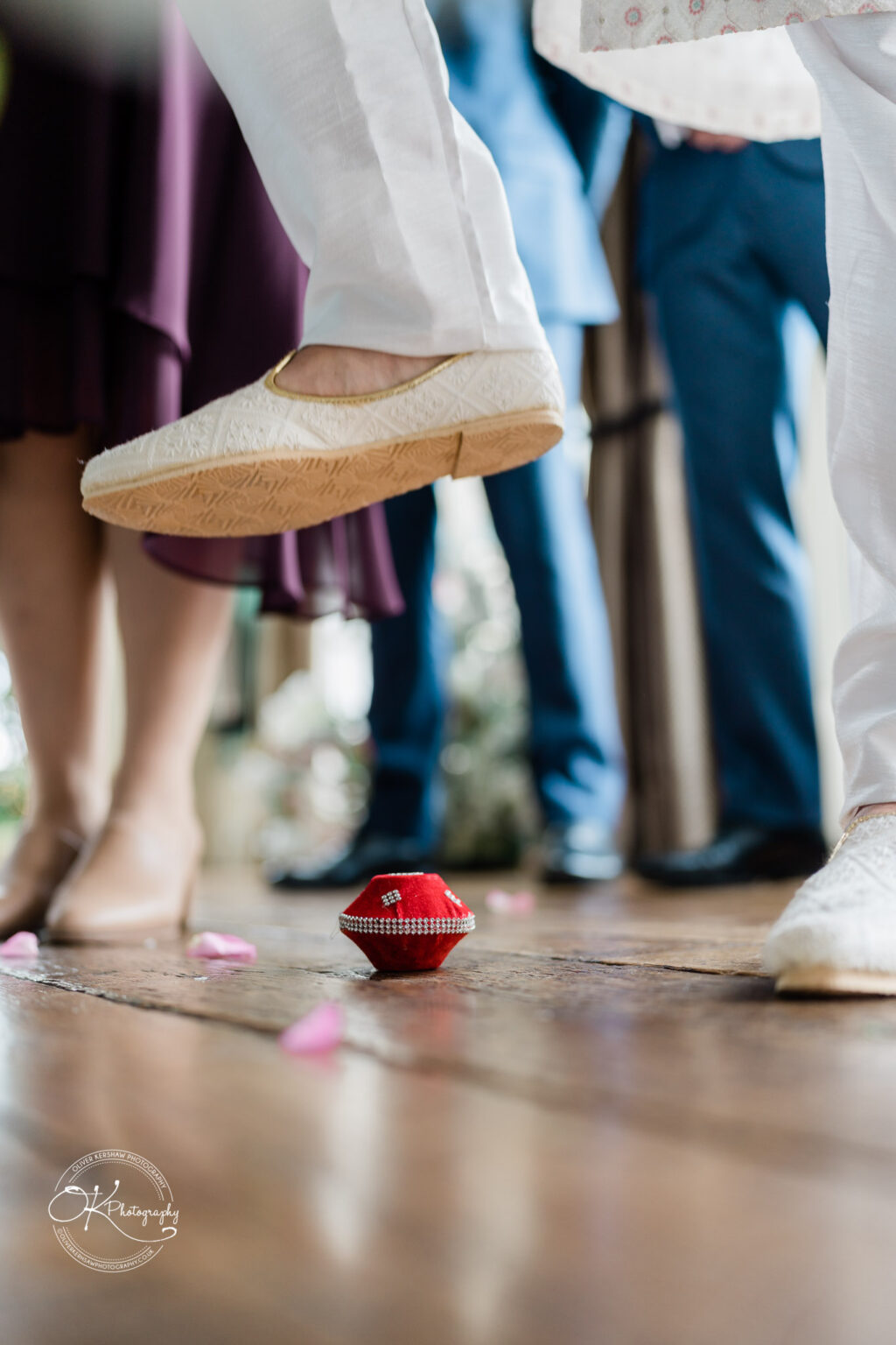 Close-up of groom's foot stepping on a traditional wedding item during a ritual.
