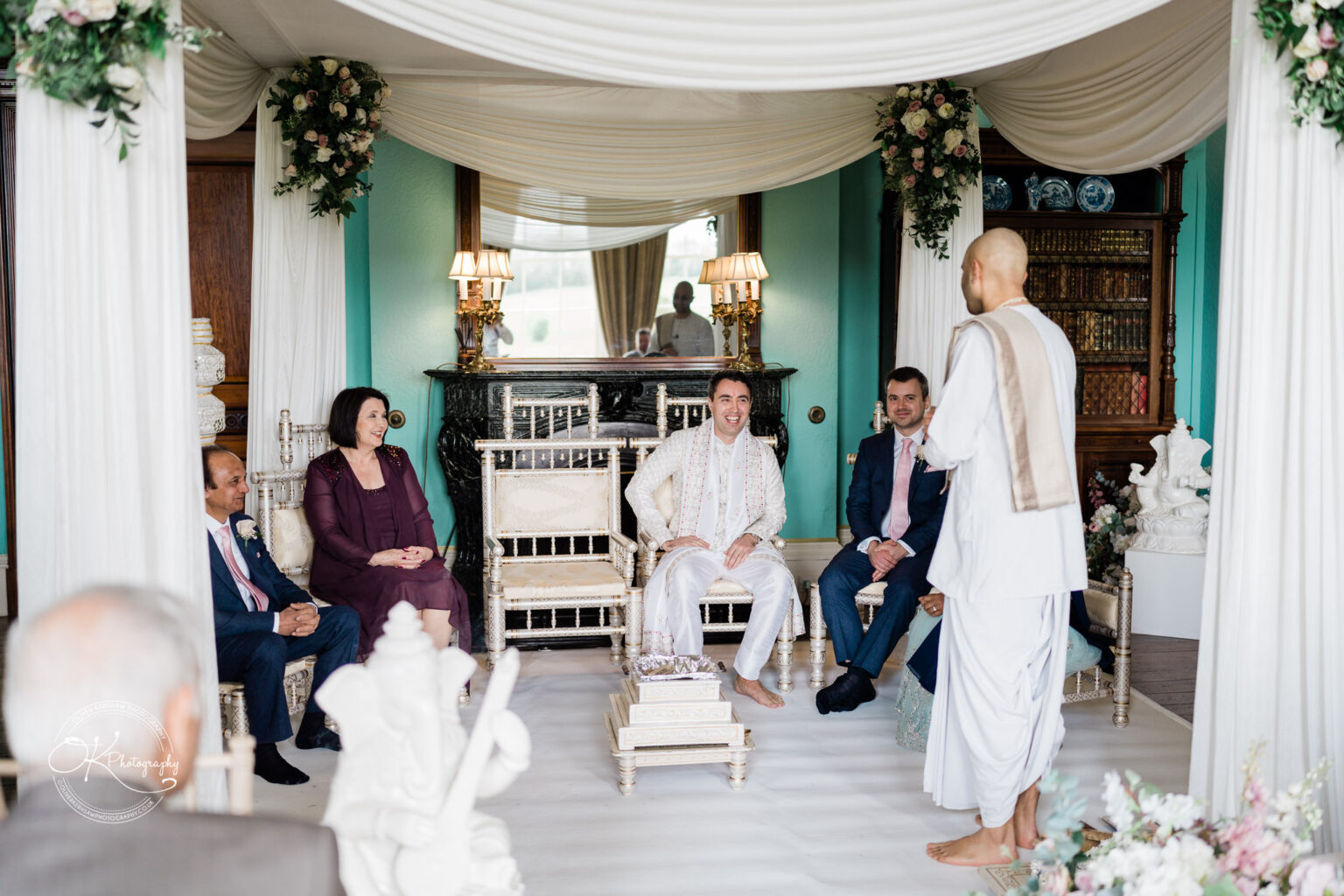 Groom seated under a decorated canopy during the Hindu wedding ceremony, with guests seated around.