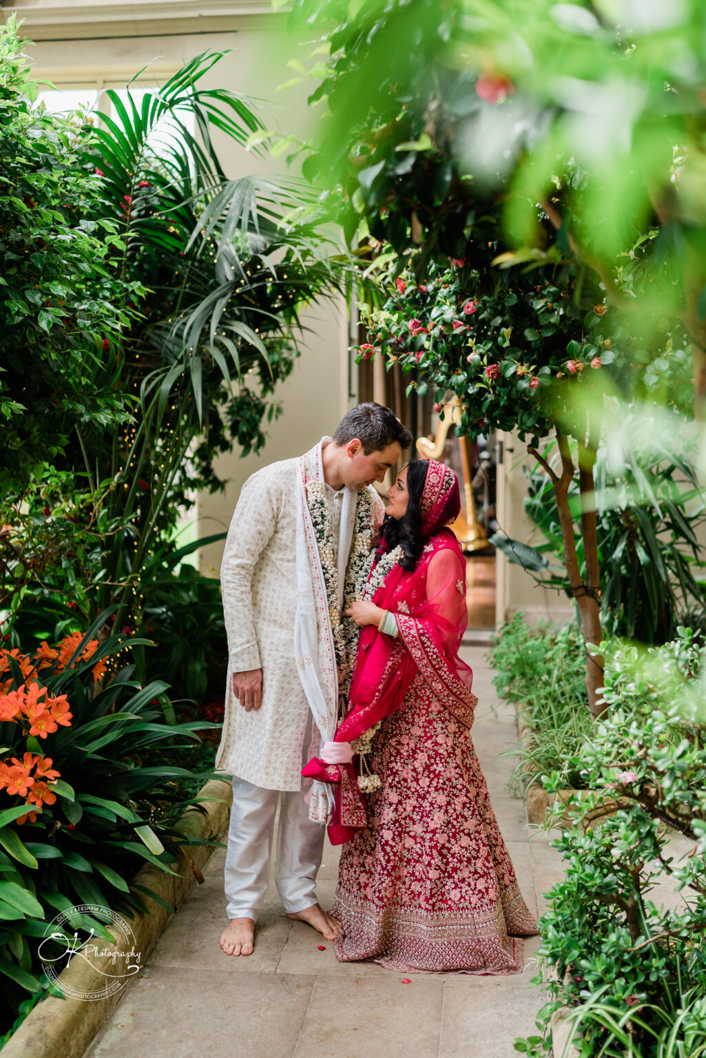Bride and groom share a tender moment in a lush garden.