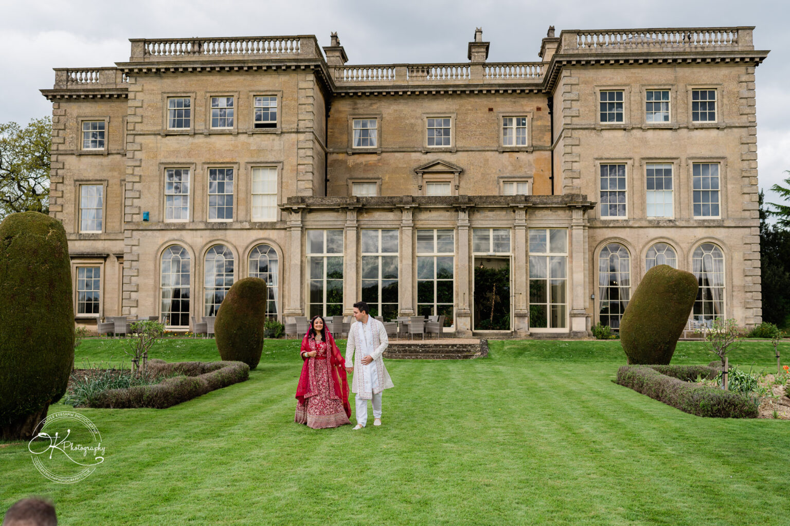 Bride and groom standing on the lawn in front of Prestwold Hall.