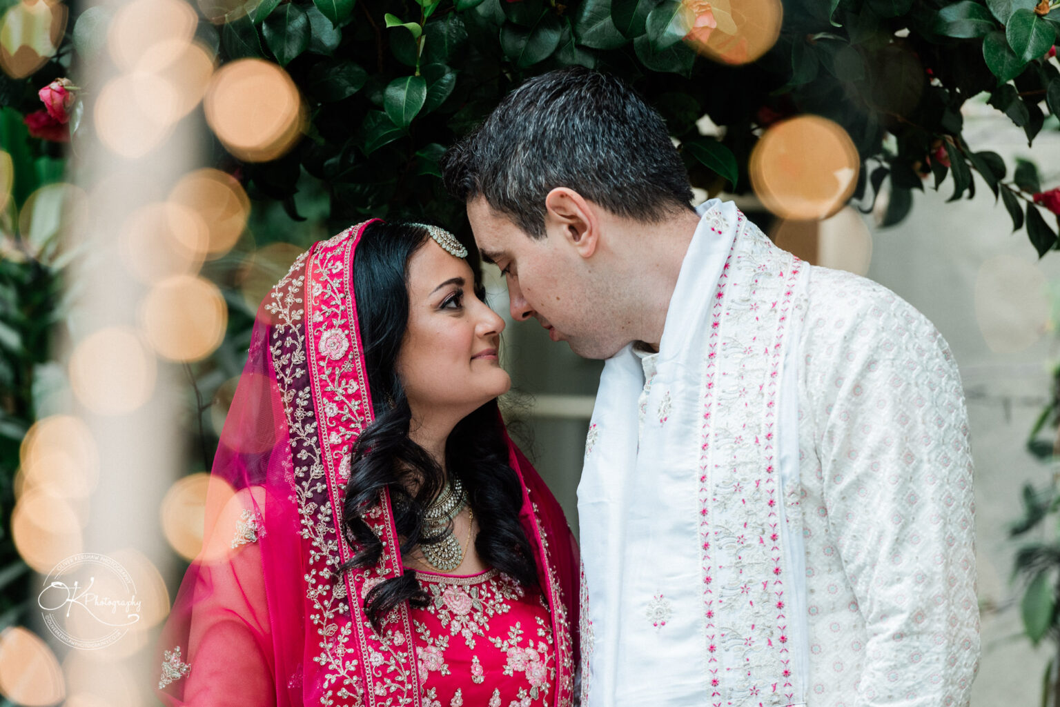 Bride and groom share an intimate moment under a tree with soft lighting.