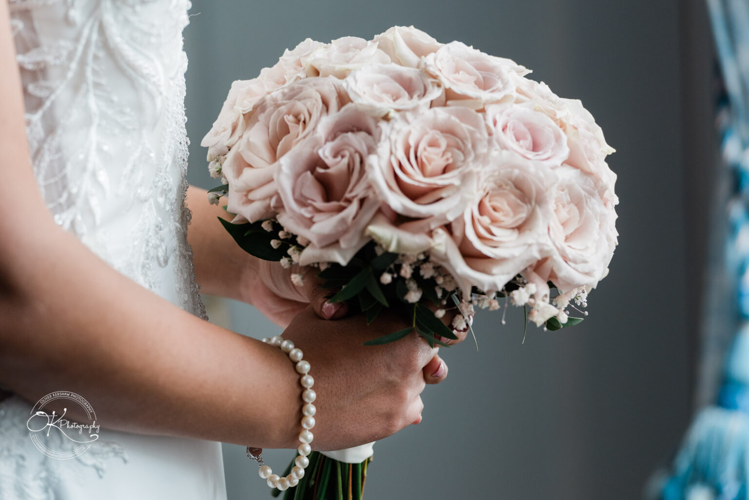 Close-up of bride holding a bouquet of pale pink roses.