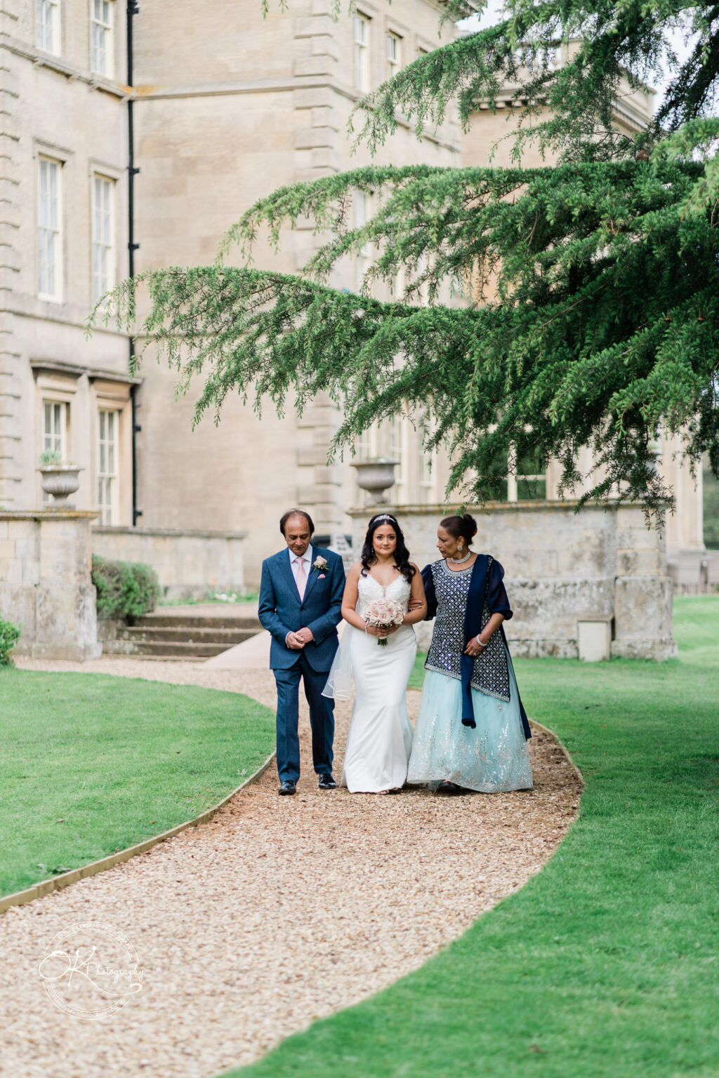 Bride walking down the aisle with her parents at Prestwold Hall