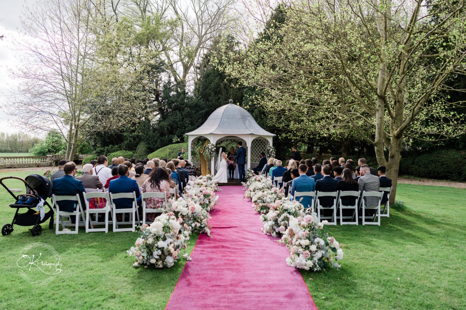 Outdoor wedding ceremony setup with pink carpet and floral arrangements at Prestwold Hall